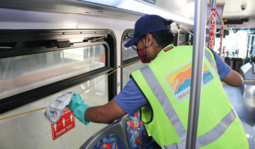 A worker is cleaning the windows of a bus.